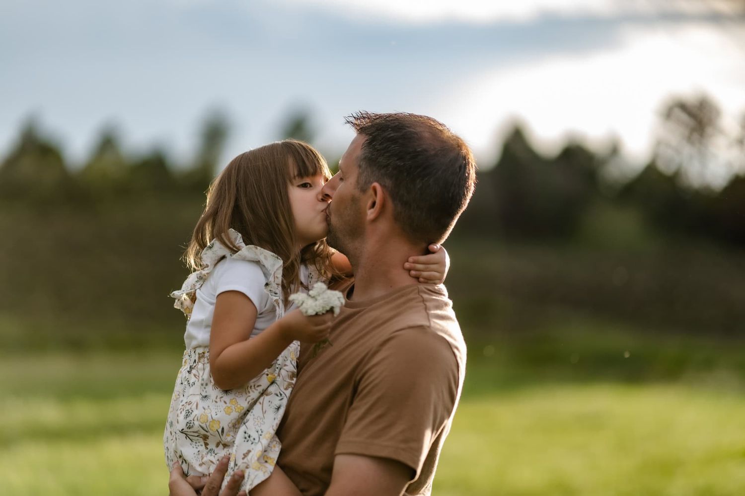 A tender moment between parent and child in a sunlit meadow.