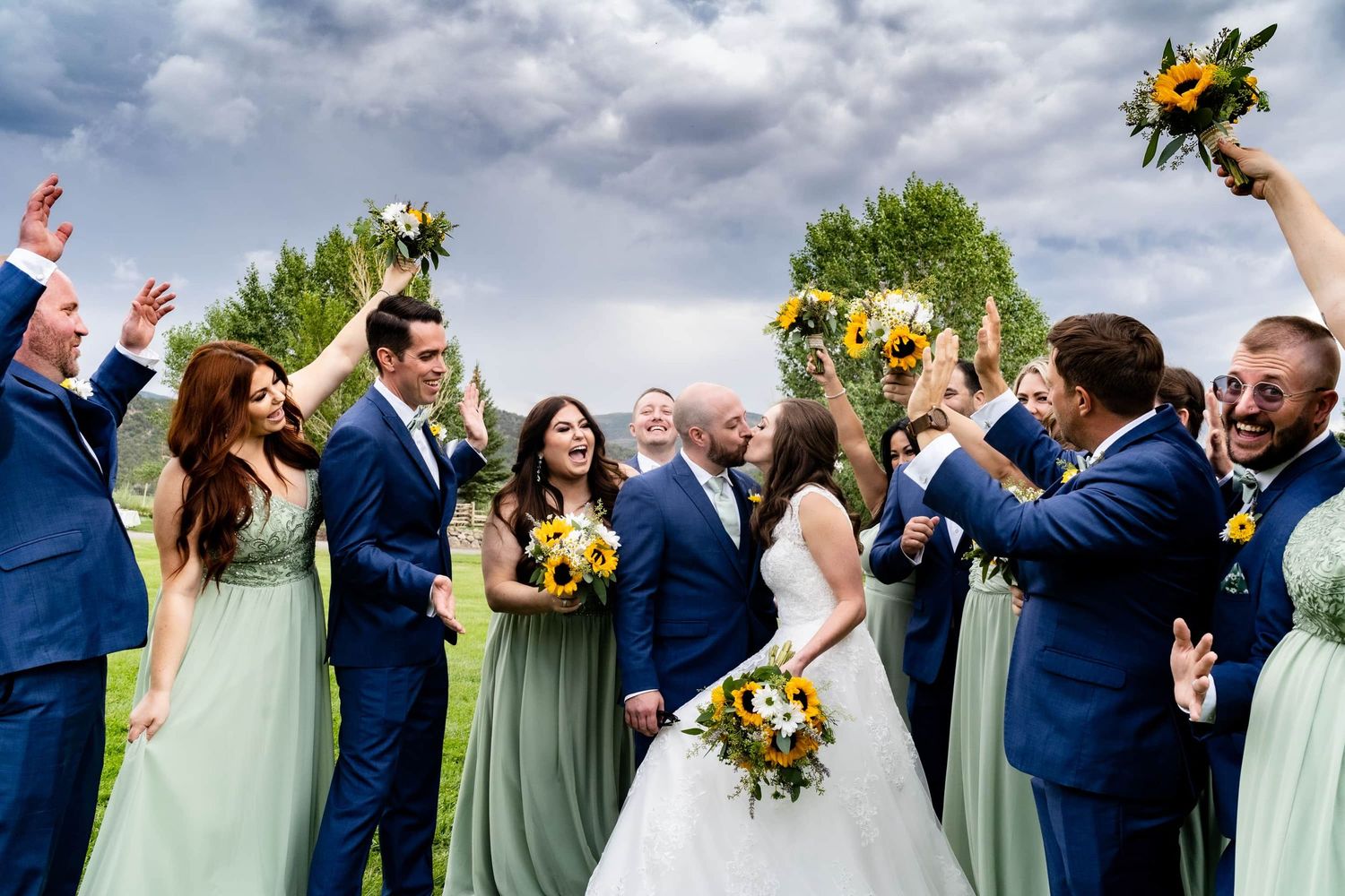 Wedding party in blue and mint green attire celebrating outdoor at one of the best Montrose wedding venues under cloudy skies.
