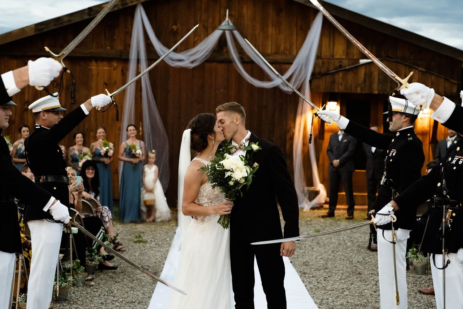 Wedding ceremony in rustic barn with white draping and lantern decorations.