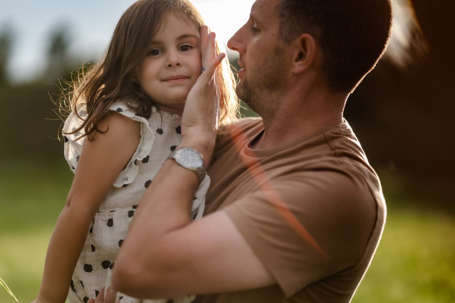 A touching moment between parent and child backlit by golden hour sunlight.