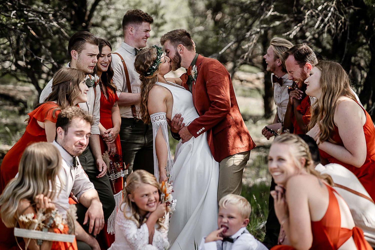 Wedding party and children gather for candid group photo in outdoor setting.