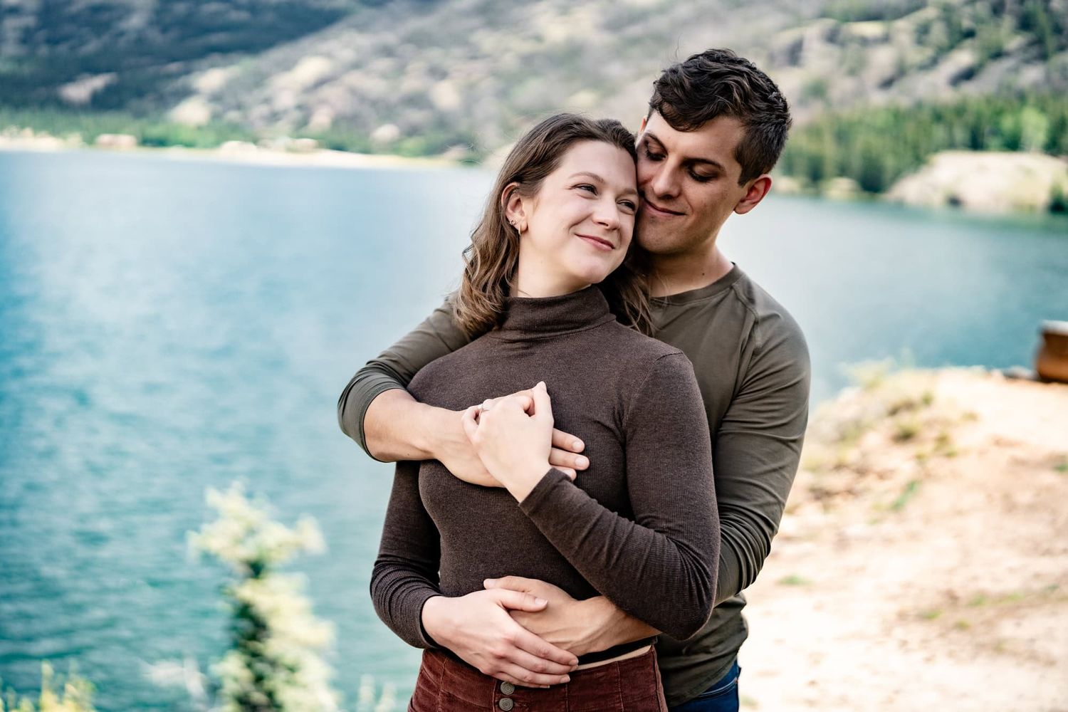 A romantic moment shared between two people by a scenic mountain lake.