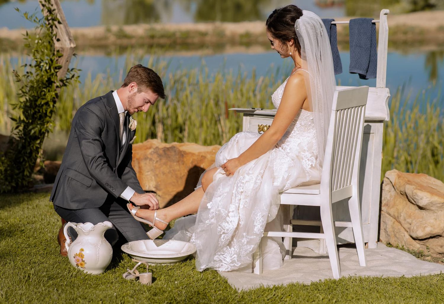 Traditional wedding foot washing ceremony outdoors by a serene pond.