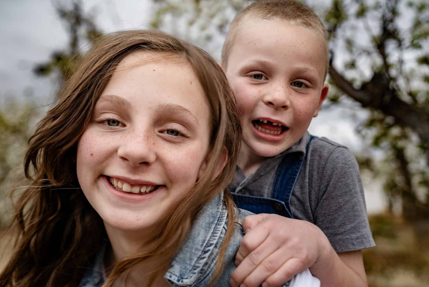 Two children sharing a joyful laugh while posing together outdoors.