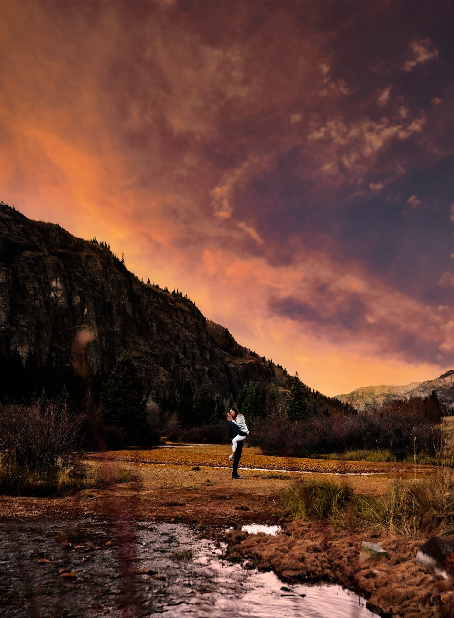 A silhouetted figure jumps for joy against a dramatic mountain sunset.