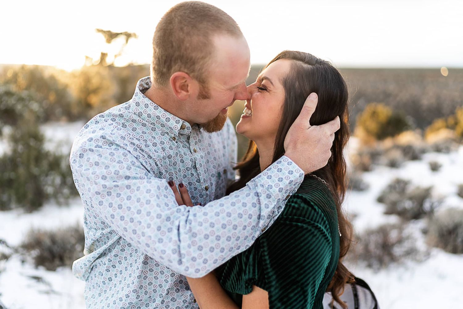 A romantic moment between a couple in a winter landscape at sunset.