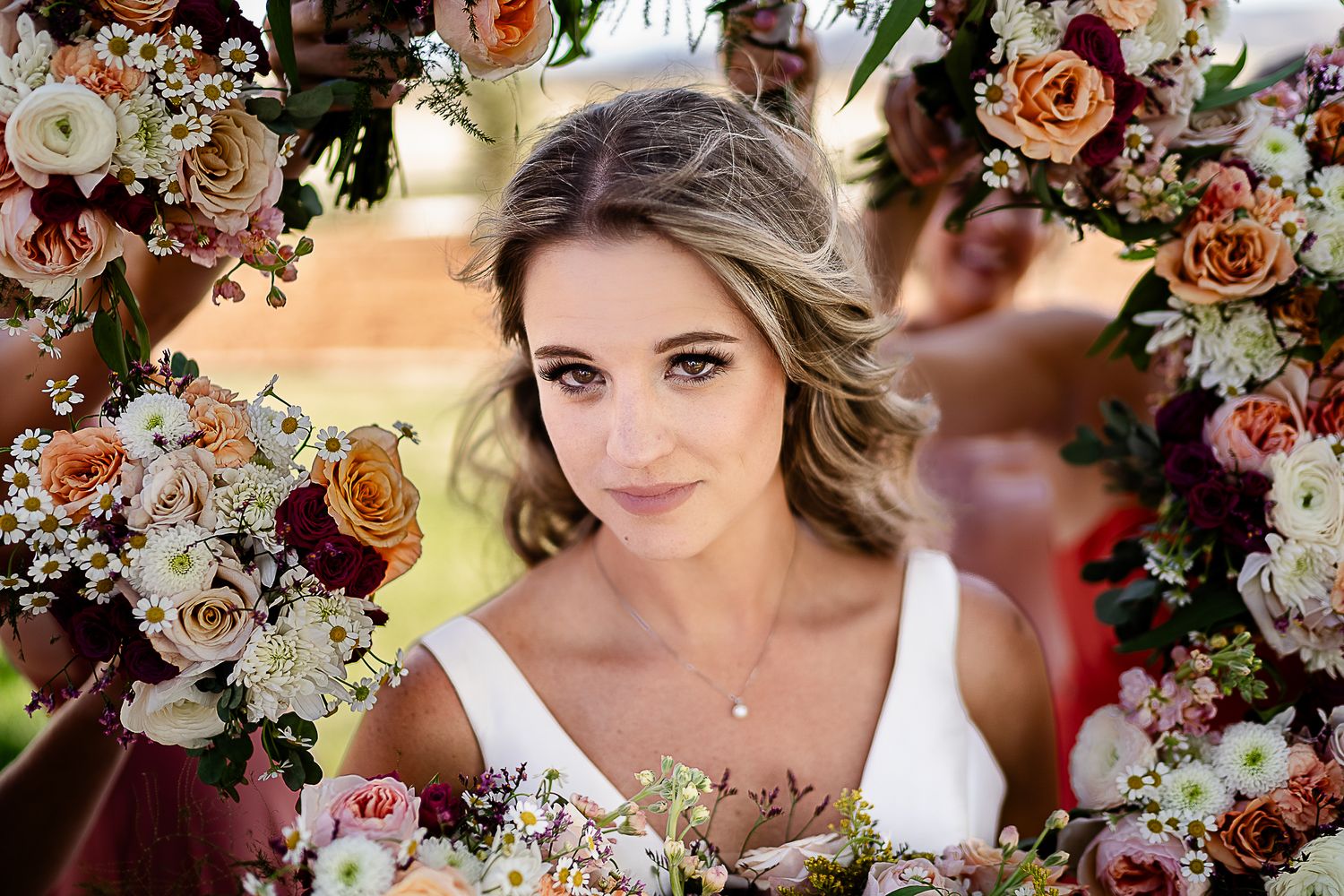 Close-up portrait through a floral arch with peach and white roses.