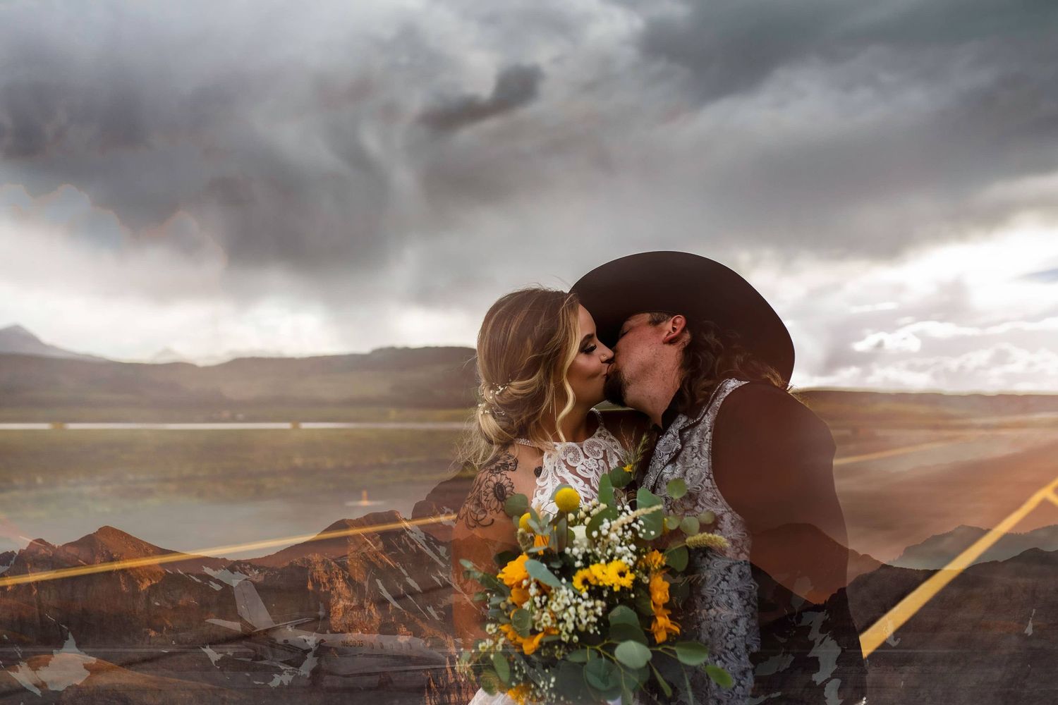 Romantic western-style wedding portrait under stormy skies with yellow wildflower bouquet.
