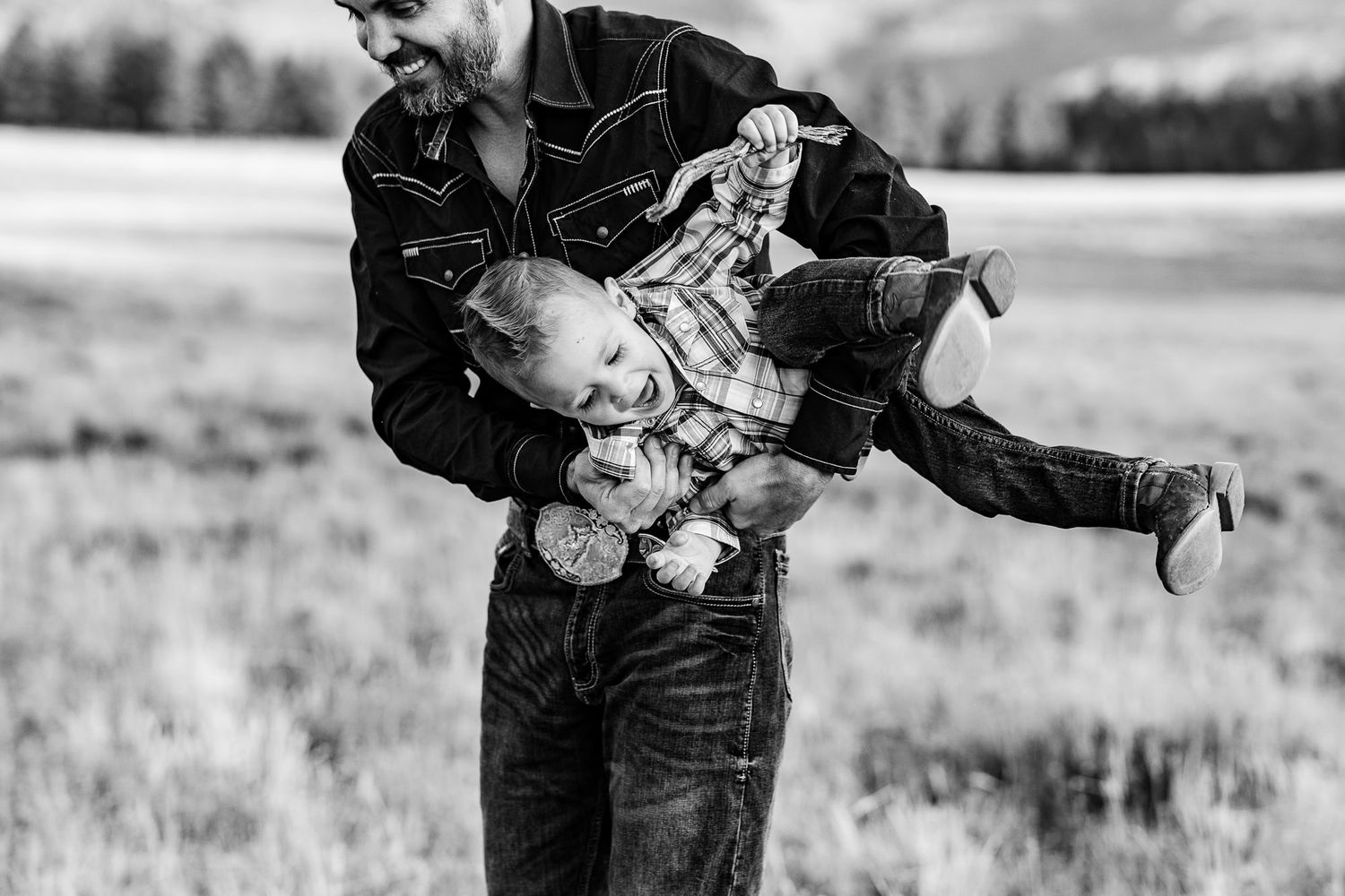 Black and white action shot of playful parent swinging child outdoors.