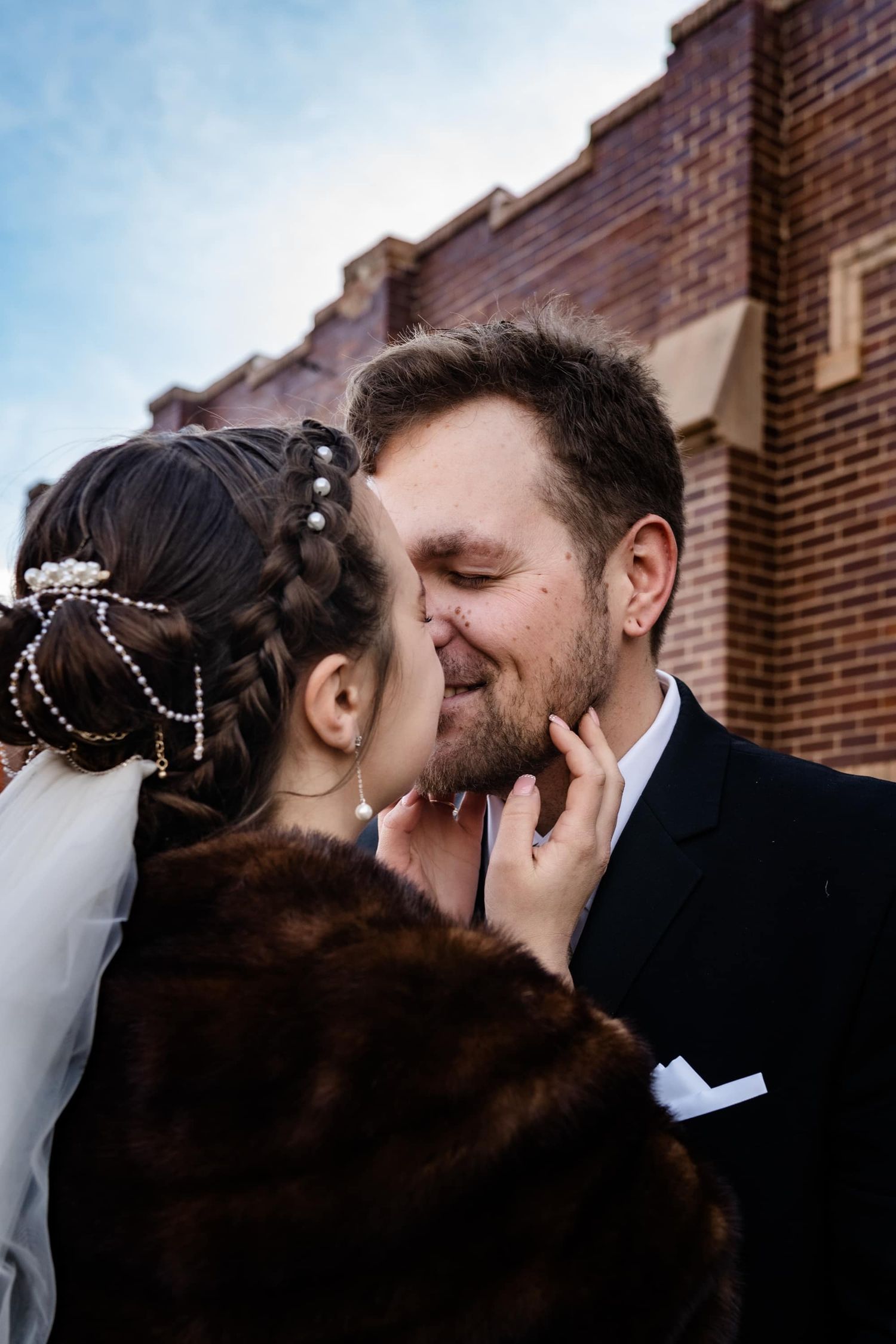Close up of newlyweds sharing an intimate moment outside a brick building.