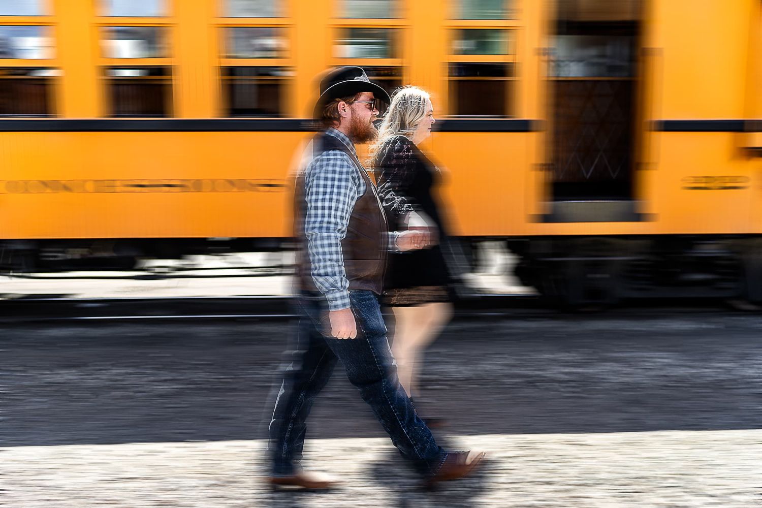 Motion blur photo of people walking past a bright yellow train car.
