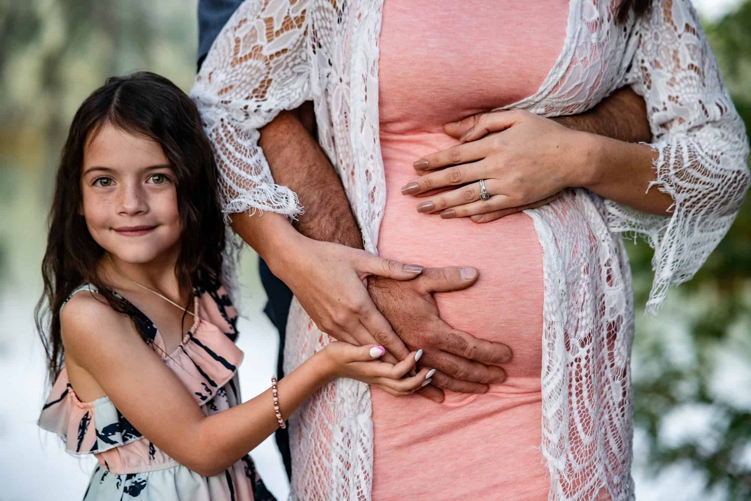 Tender pregnancy photo with child embracing mother's baby bump.