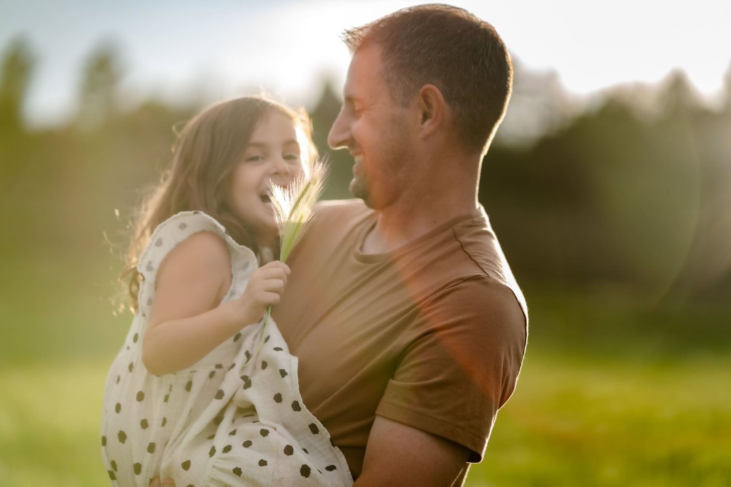 Parent and child sharing a joyful moment together in a sunlit meadow.