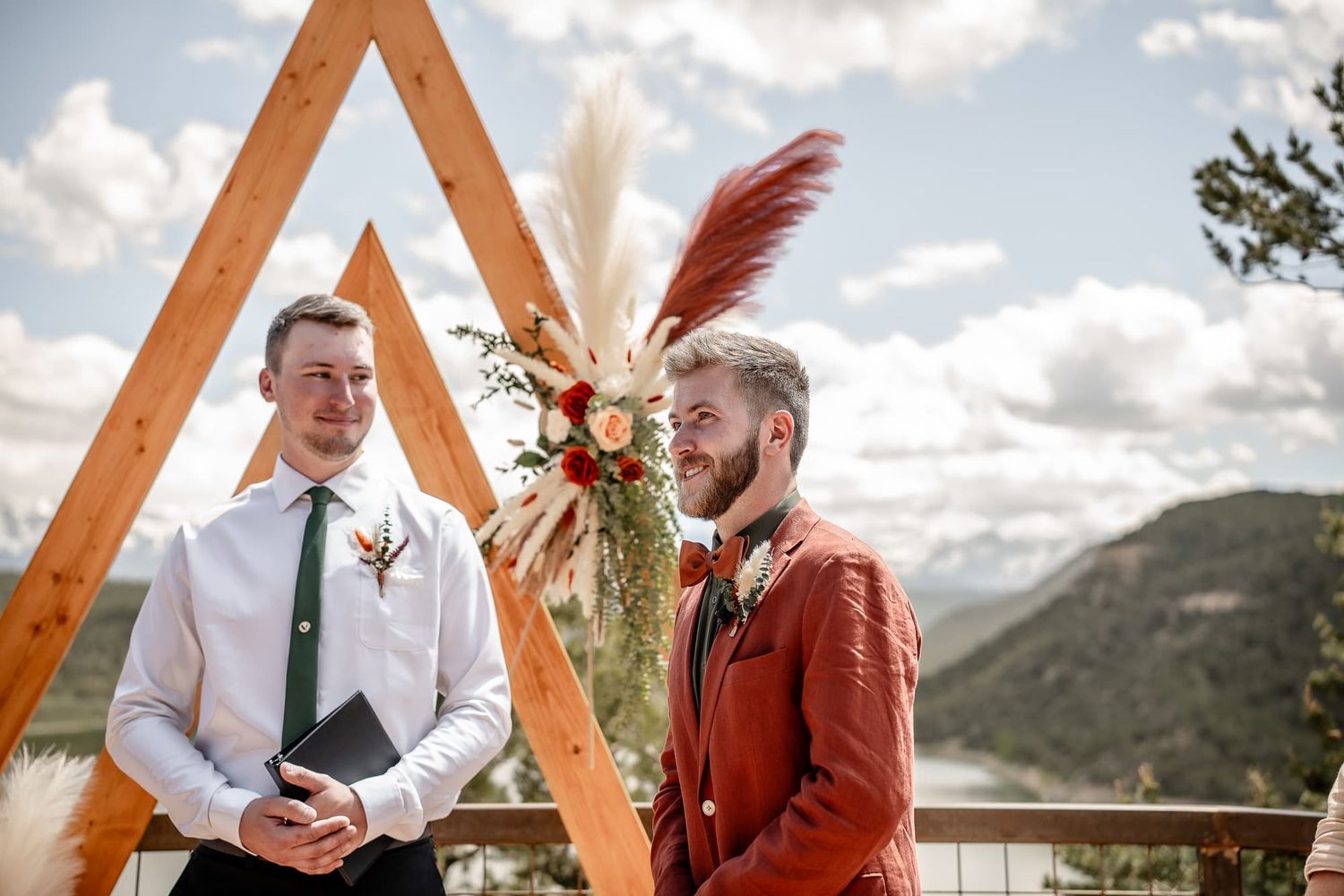 Boho outdoor wedding ceremony with wooden triangle arch and mountain backdrop. Located at an elopement Venue with mountain views in Ridgway.