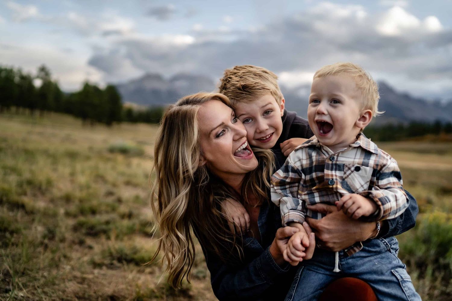Loving family moment captured outdoors with mountain range in background. Family photos with mountain views near Ridgway Colorado.