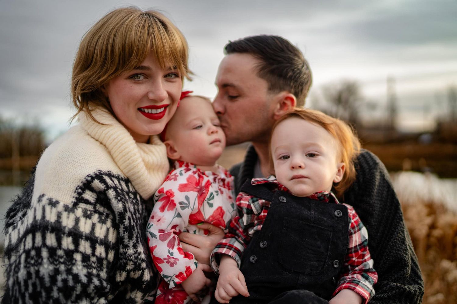 A family of four shares a tender moment together outdoors in winter attire.