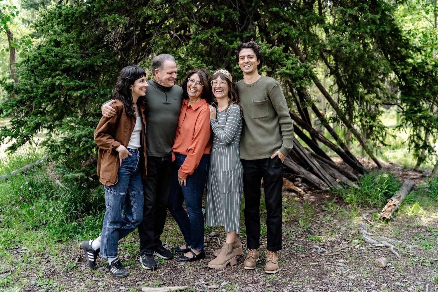 Group poses together against lush green forest backdrop in casual outdoor setting.
