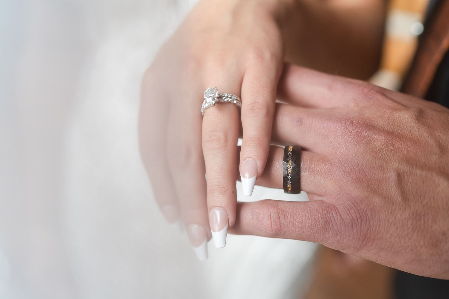 Close-up of wedding rings being exchanged, showing detailed diamond engagement ring.