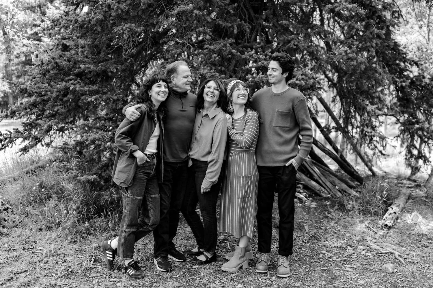 A group poses together for a casual outdoor portrait under a large tree.