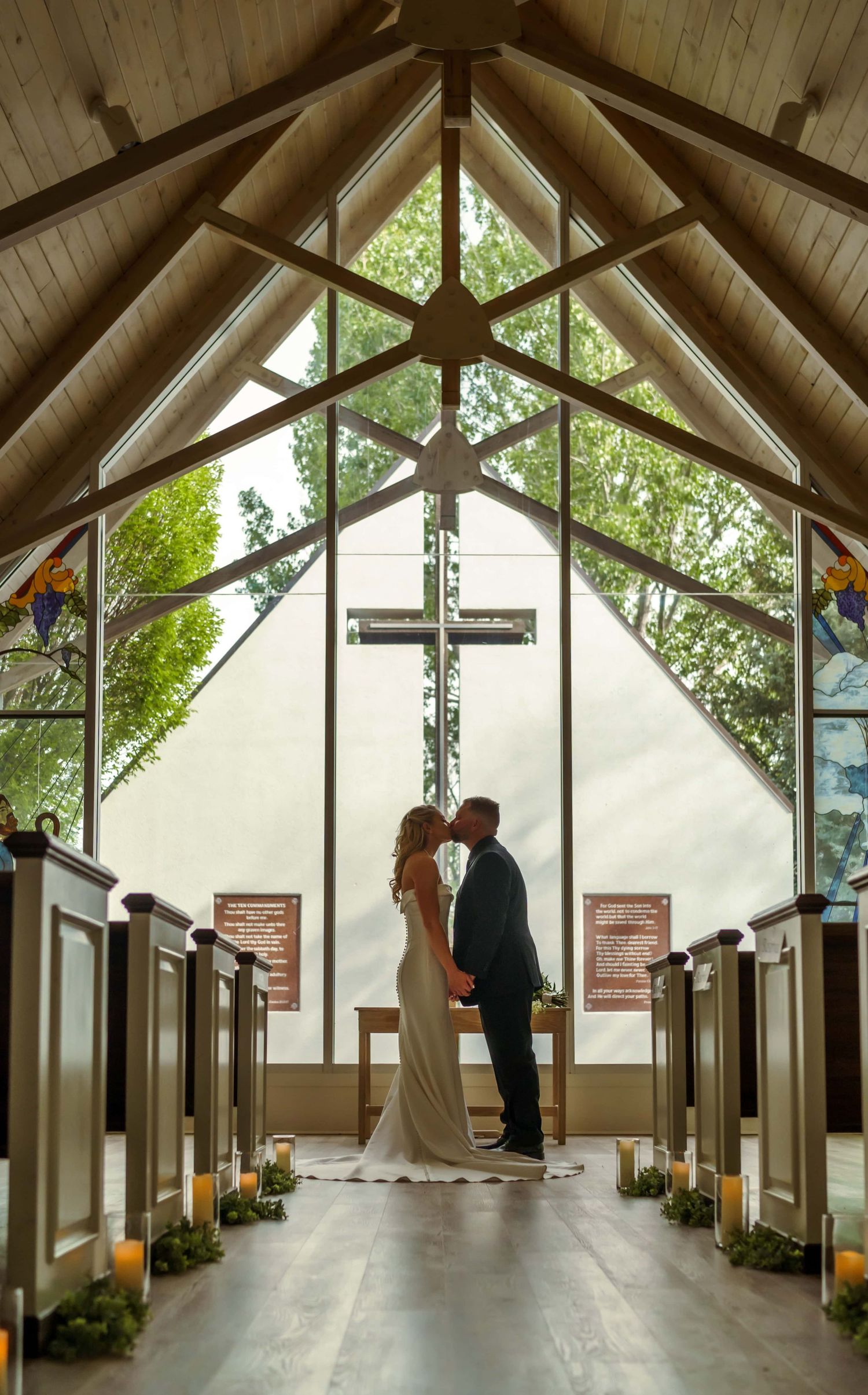 A silhouette in a chapel wedding venue in Colorado with a cross and stained glass windows. Photo by Christian Colorado wedding photographer.