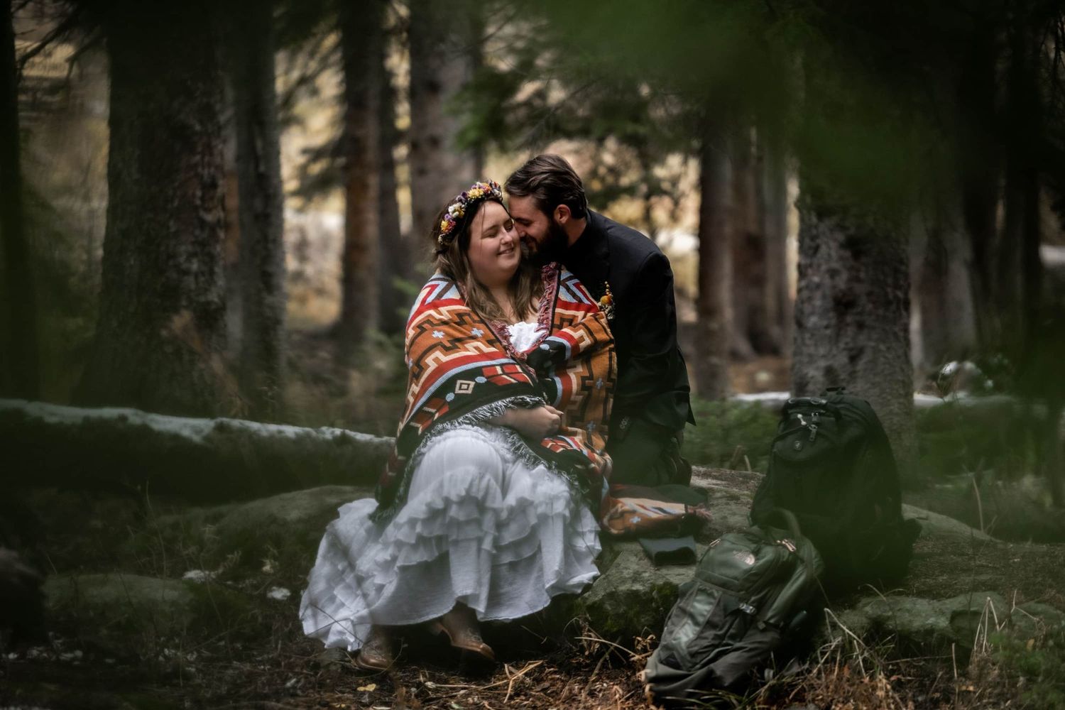 A couple embraces while sitting in a misty forest on Kebler Pass Captured by Crested Butte, Colorado Photographers