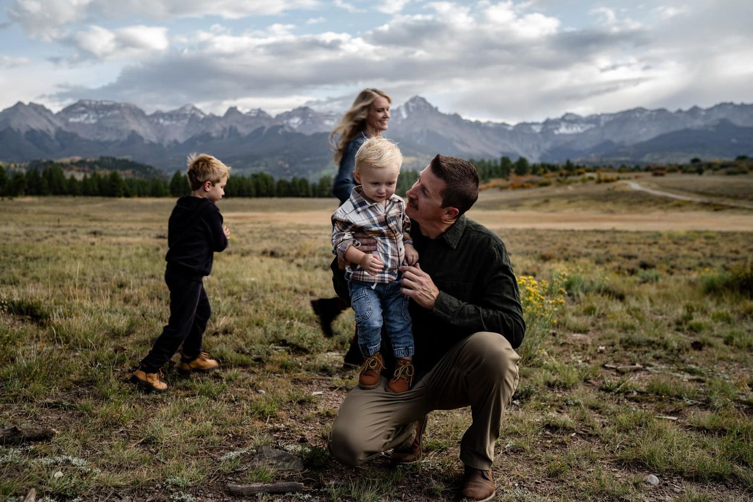 Family spending time together in a mountain meadow with spectacular mountain peaks in the background.