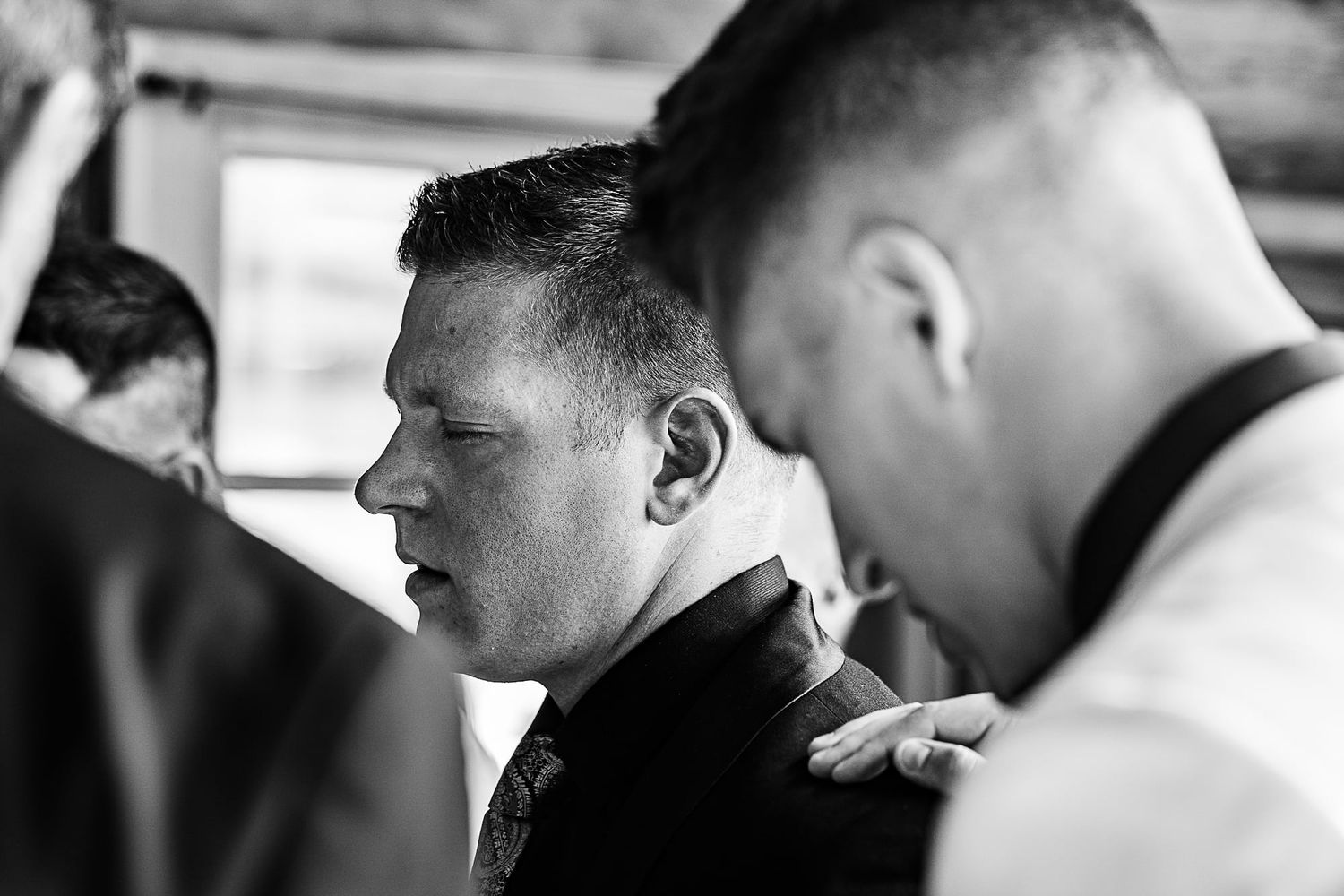 A candid black and white moment captured during wedding preparations.