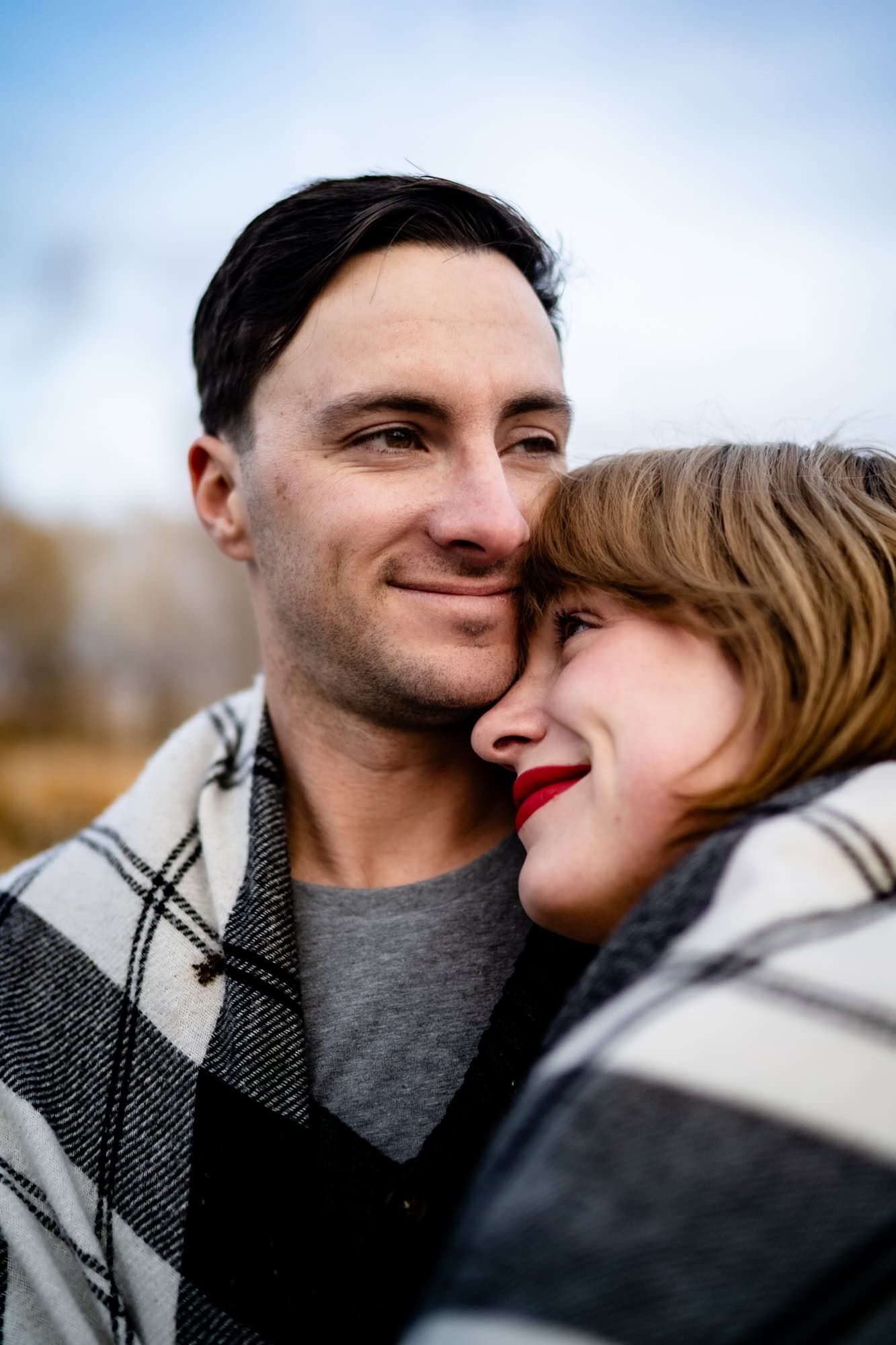 Intimate portrait of couple in winter clothing sharing a tender moment outdoors.