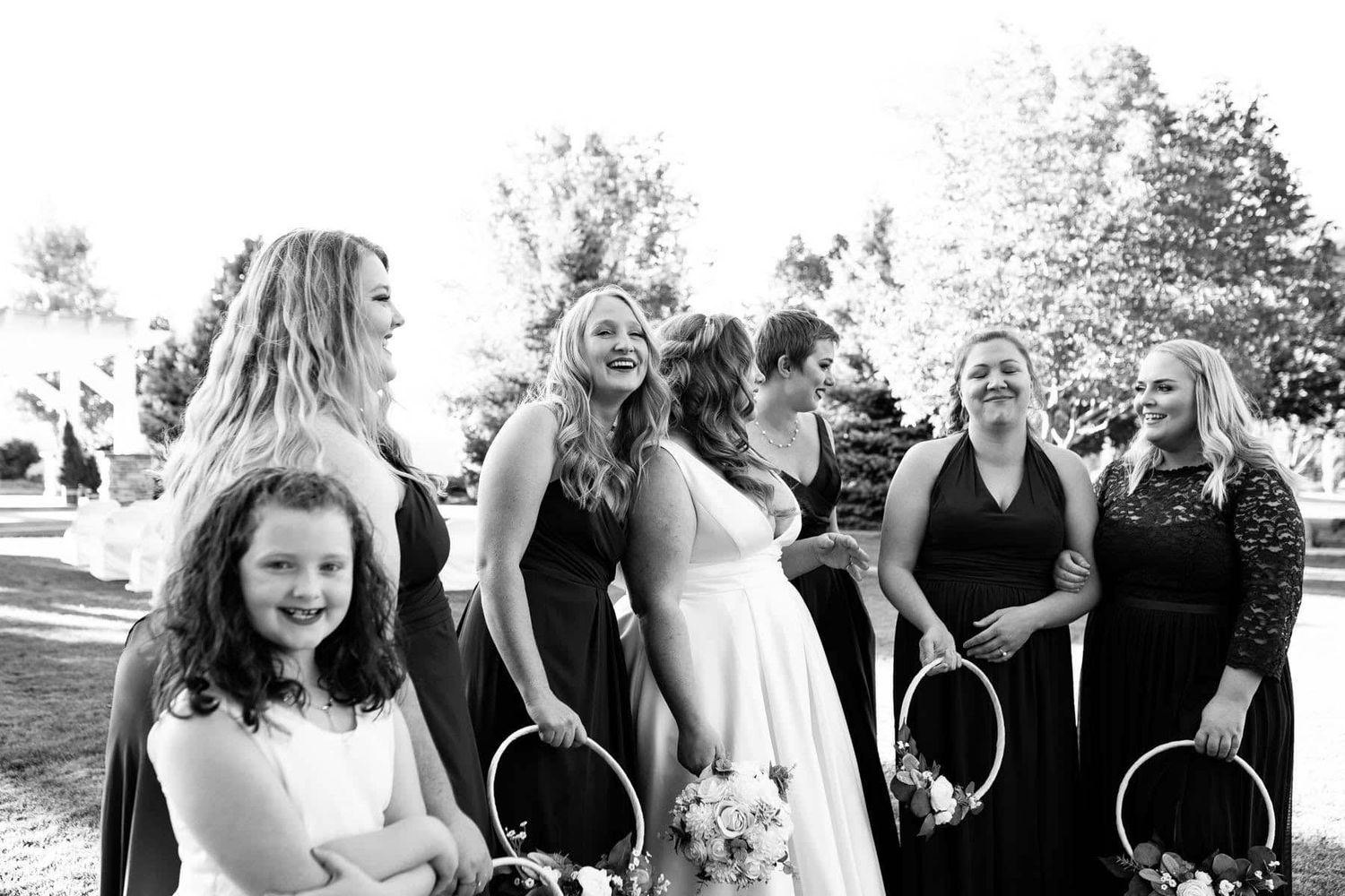 A black and white candid moment of joy at an outdoor wedding celebration.