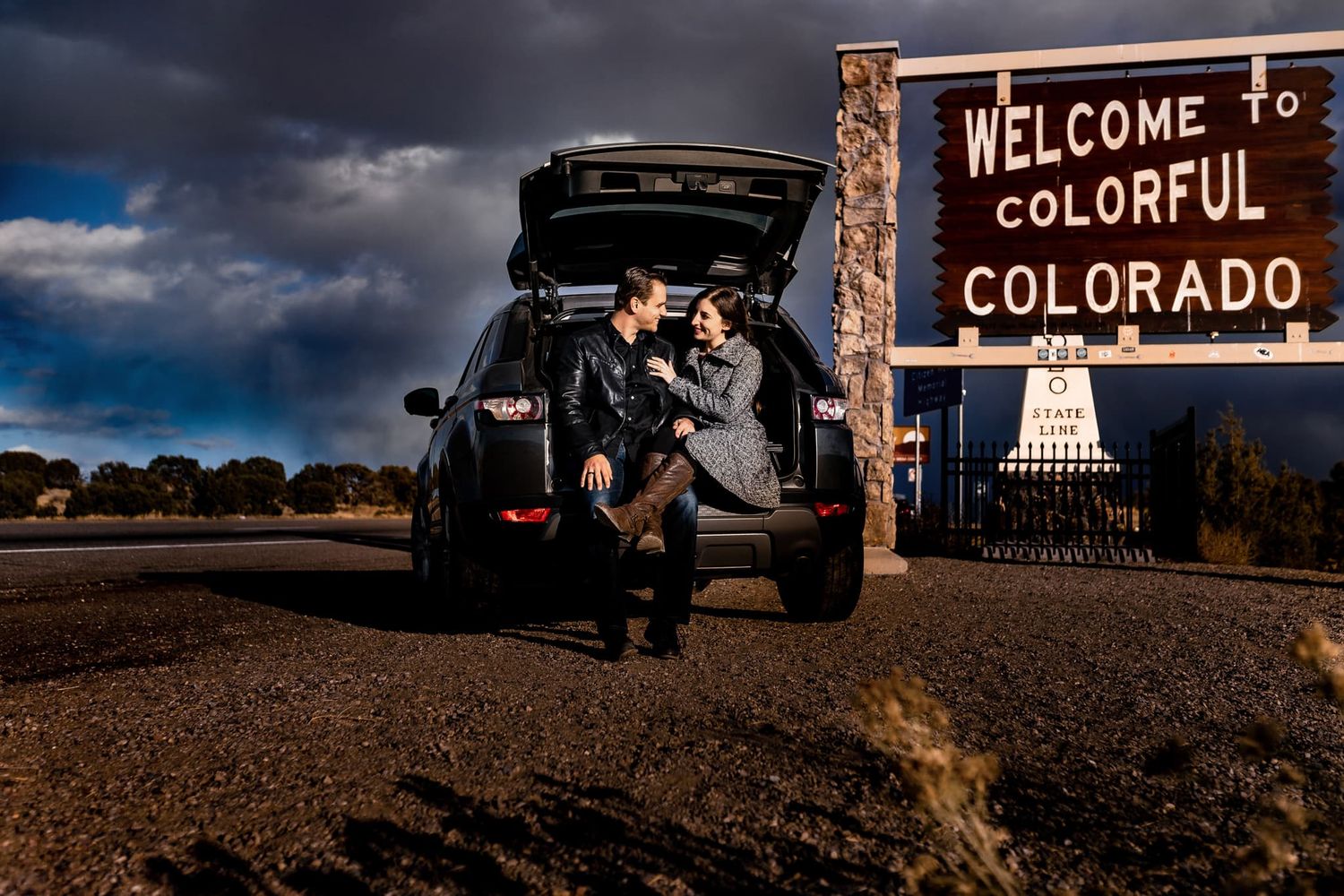 A traveler poses by the Welcome to Colorful Colorado sign at sunset.