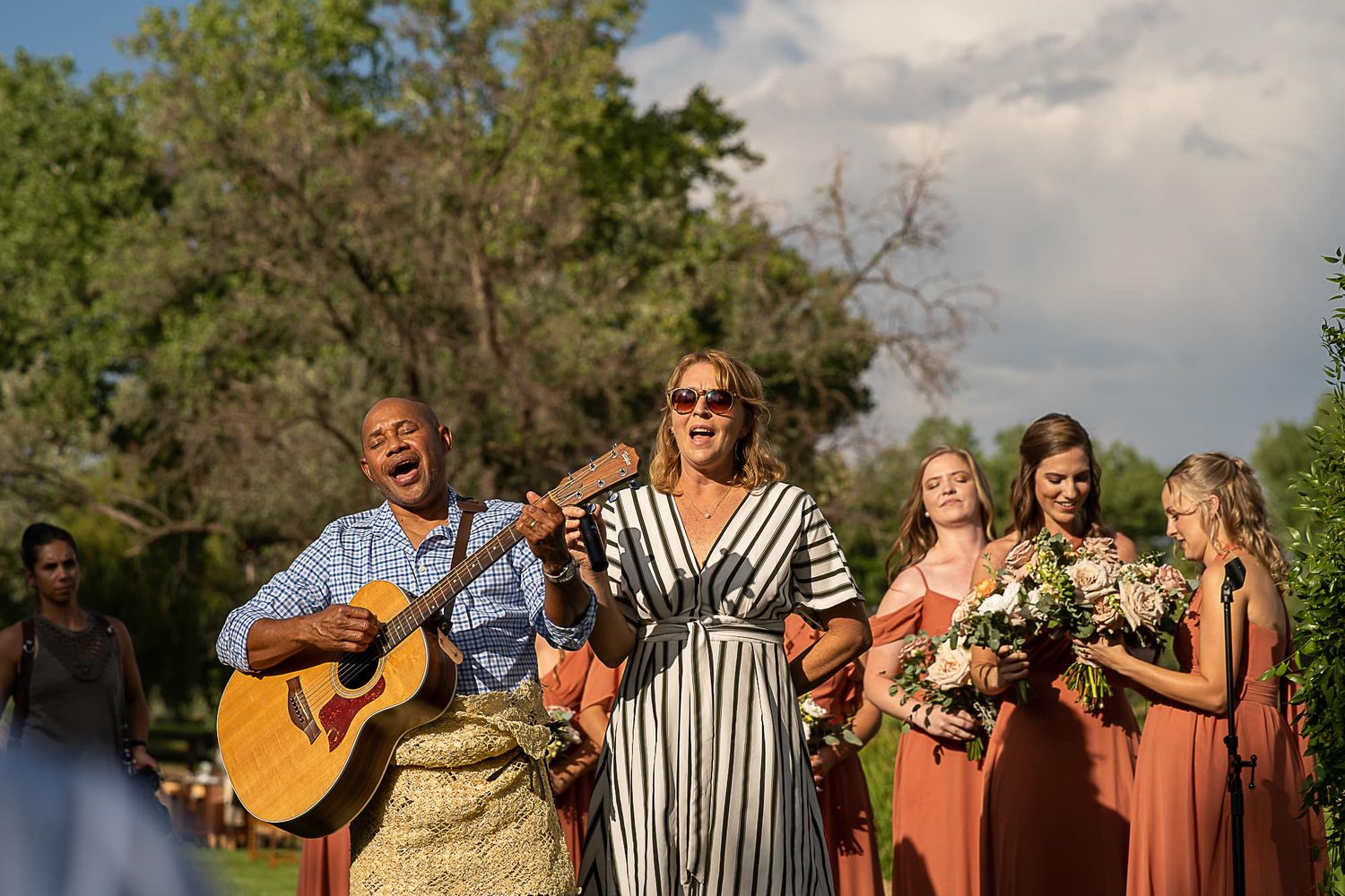 Wedding ceremony music performance with guitarist and singers in outdoor setting.