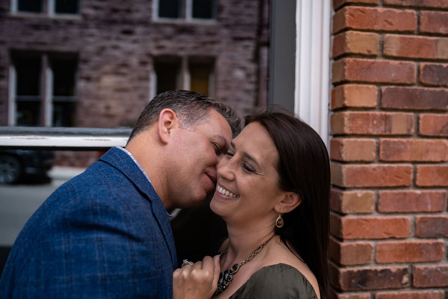 Tender moment shared between couple against brick wall background.