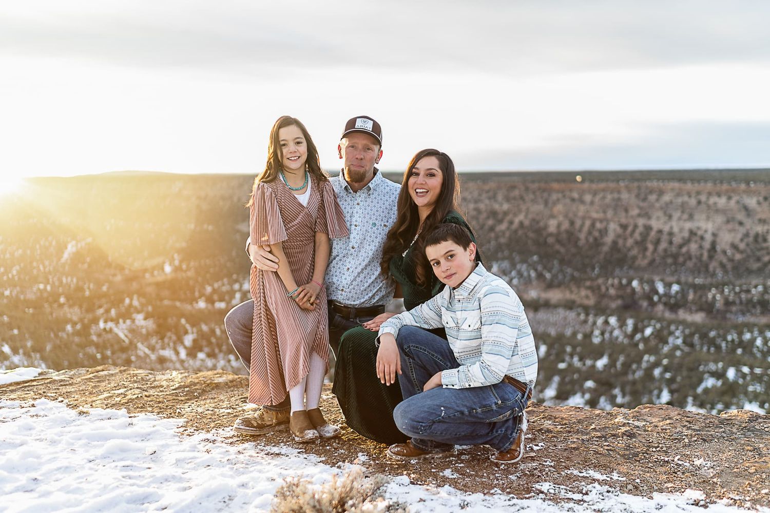 A family of four poses together outdoors during golden hour on a winter day.