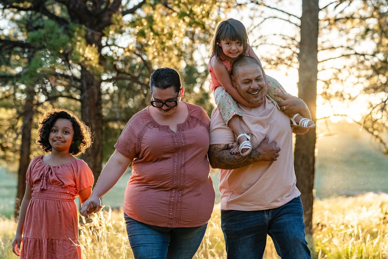 A family enjoying a playful walk together in a sunlit forest setting.