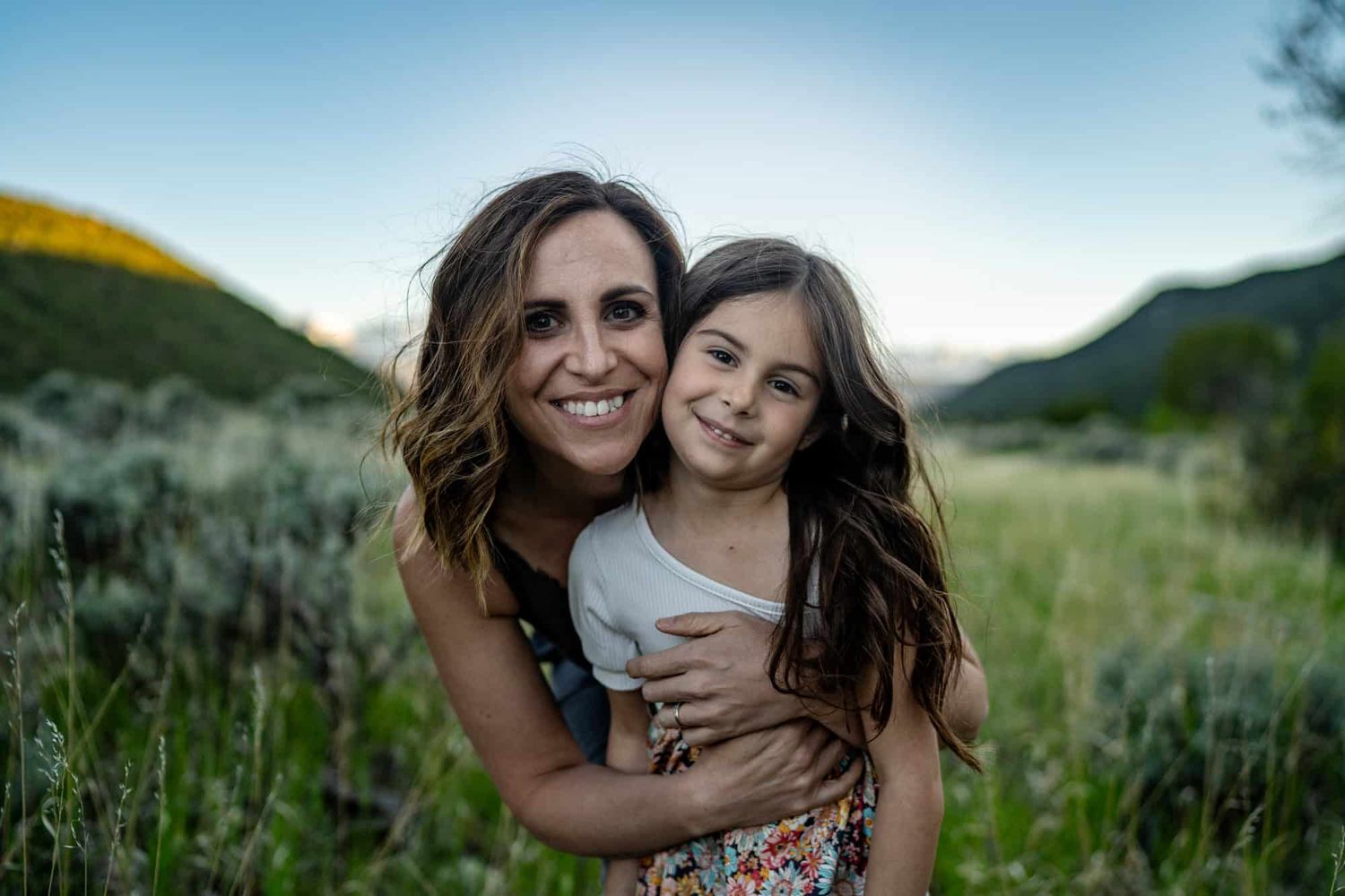 Joyful moment shared in a meadow with mountains and wildflowers in the background.