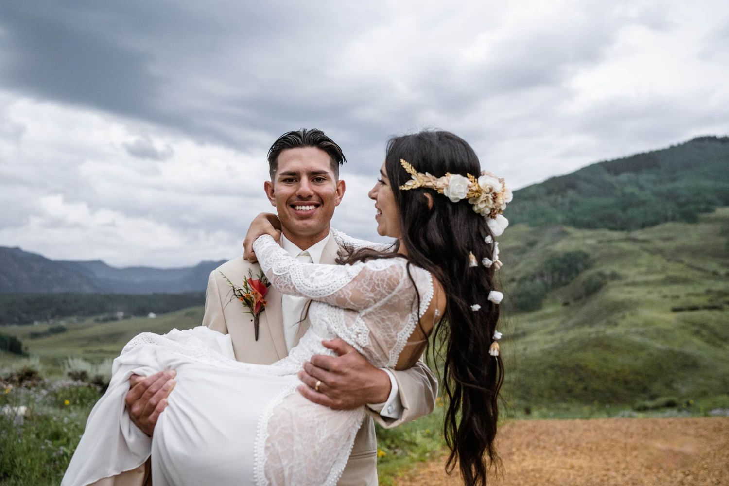 A romantic wedding portrait in rolling green mountains with dramatic cloudy skies. Affordable mountain garden wedding venues