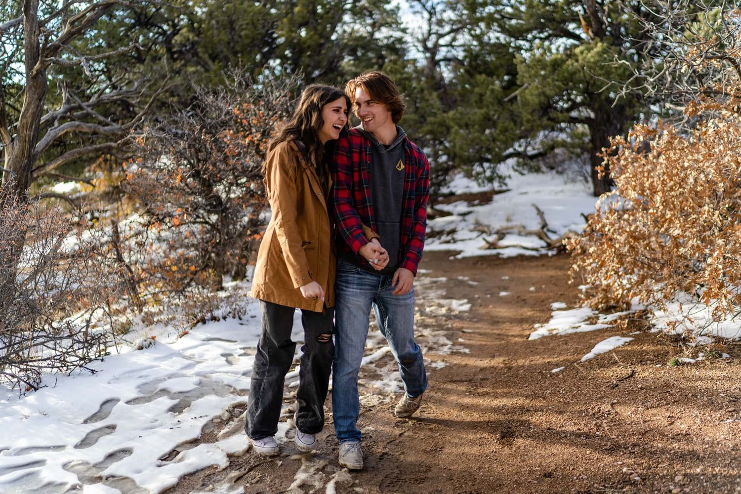 A romantic winter walk along a snowy mountain path surrounded by evergreen trees.