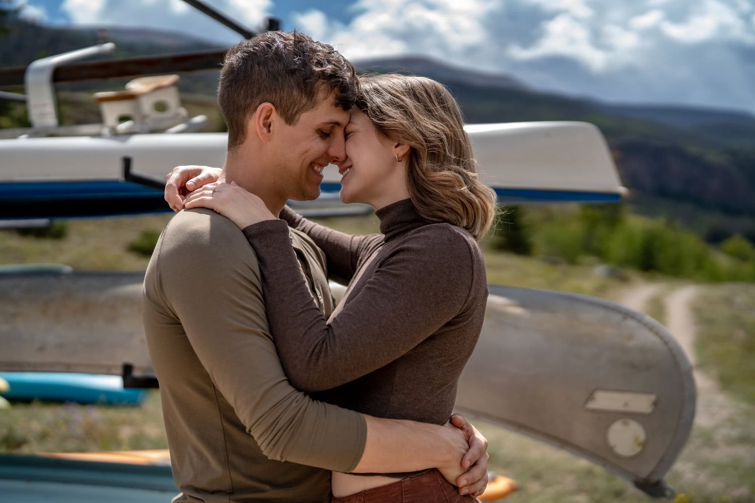 Tender moment shared between two people with mountain scenery and a vehicle in the background.