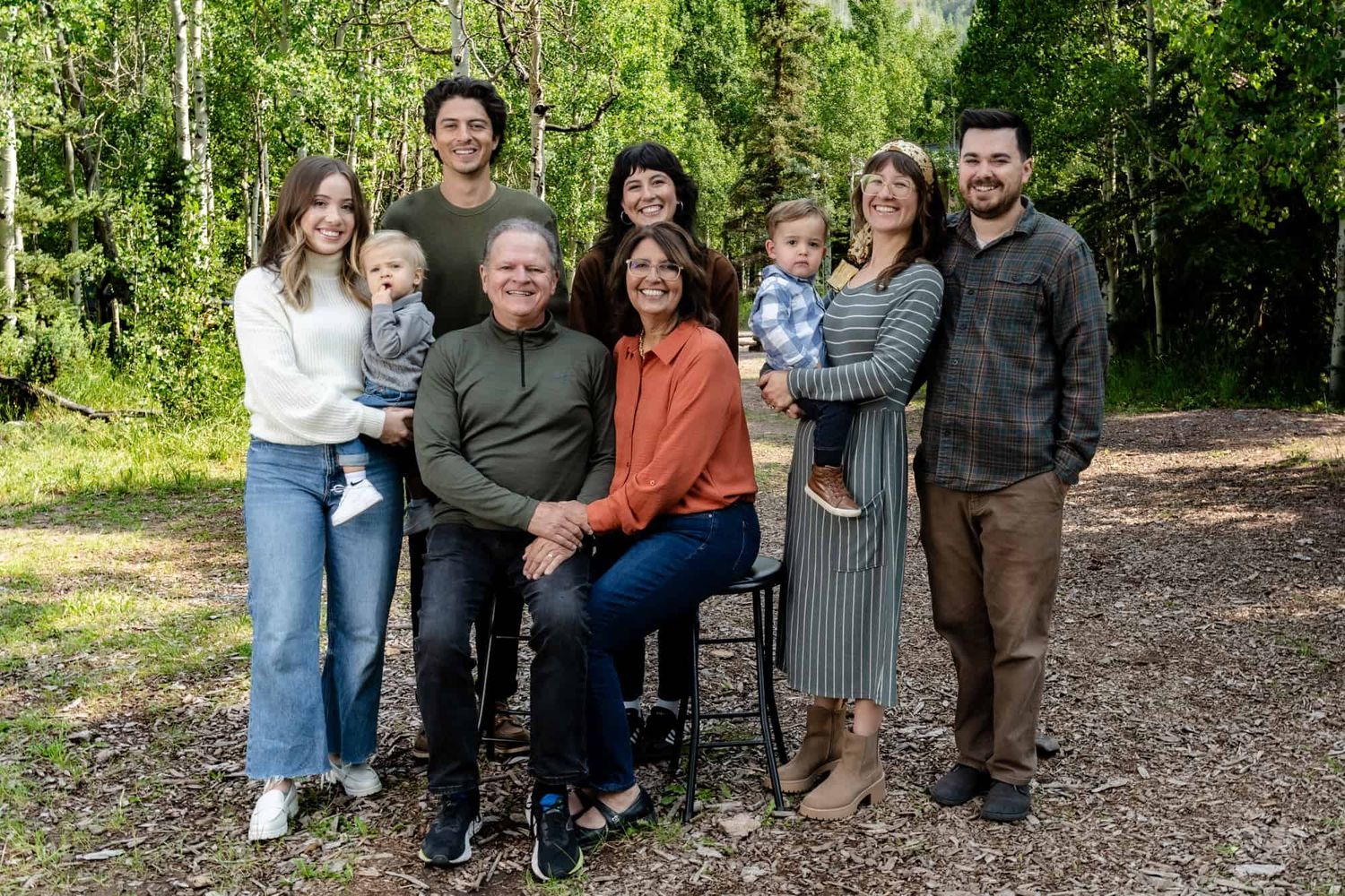 Extended family posing together for portrait in wooded outdoor setting.