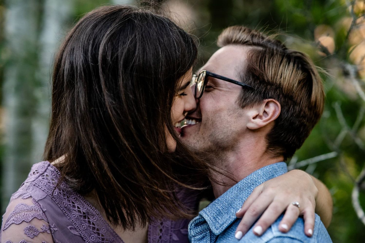 An intimate moment shared between a couple surrounded by natural greenery.