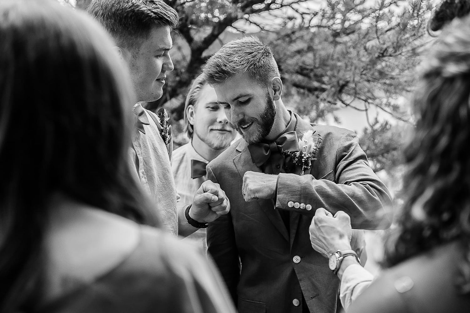 Wedding guests gather around in black and white emotional moment.