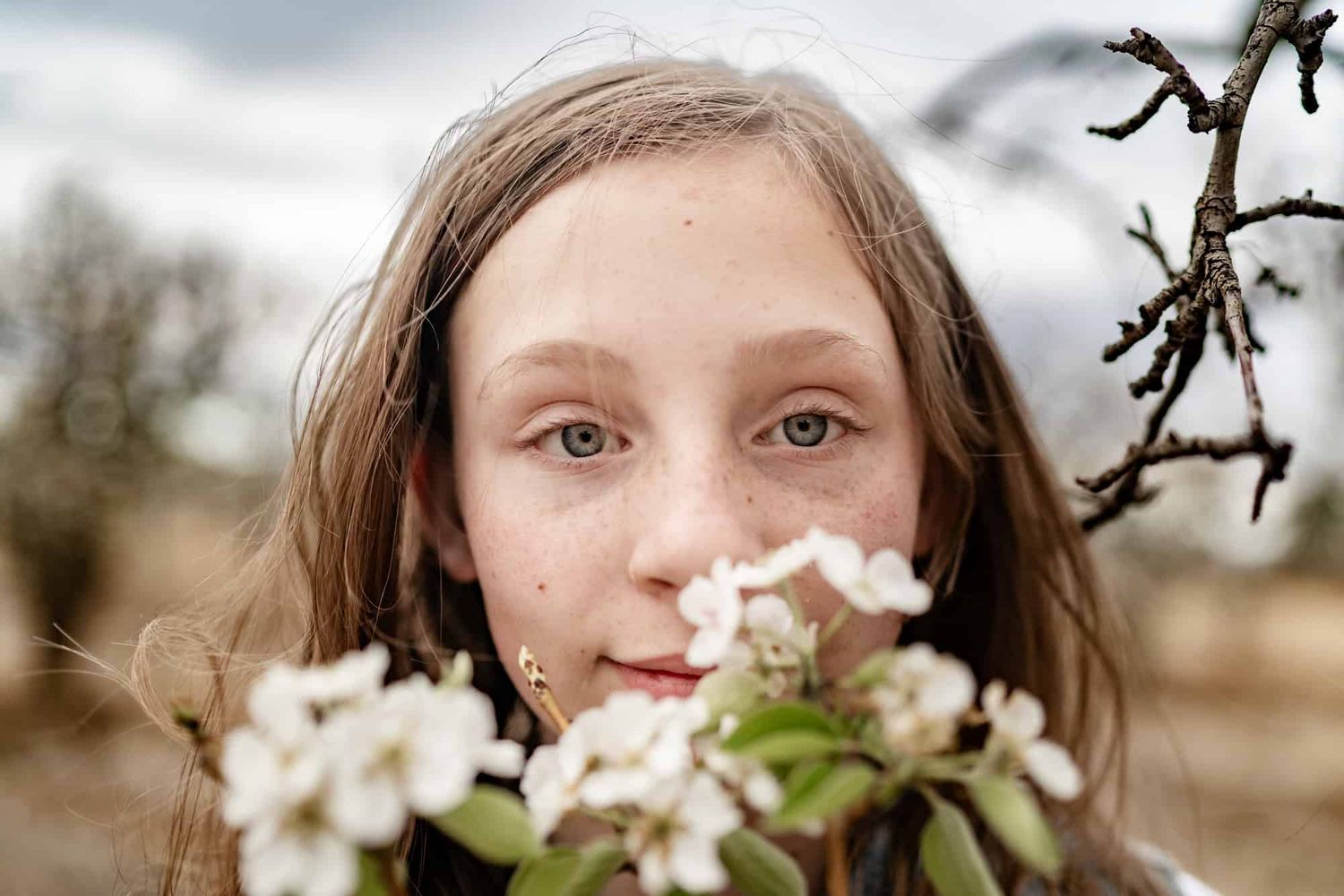 Young person admiring spring blossoms with white flowers in foreground.