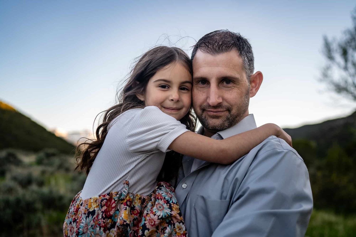 Sweet embrace captured against mountain backdrop during golden hour.