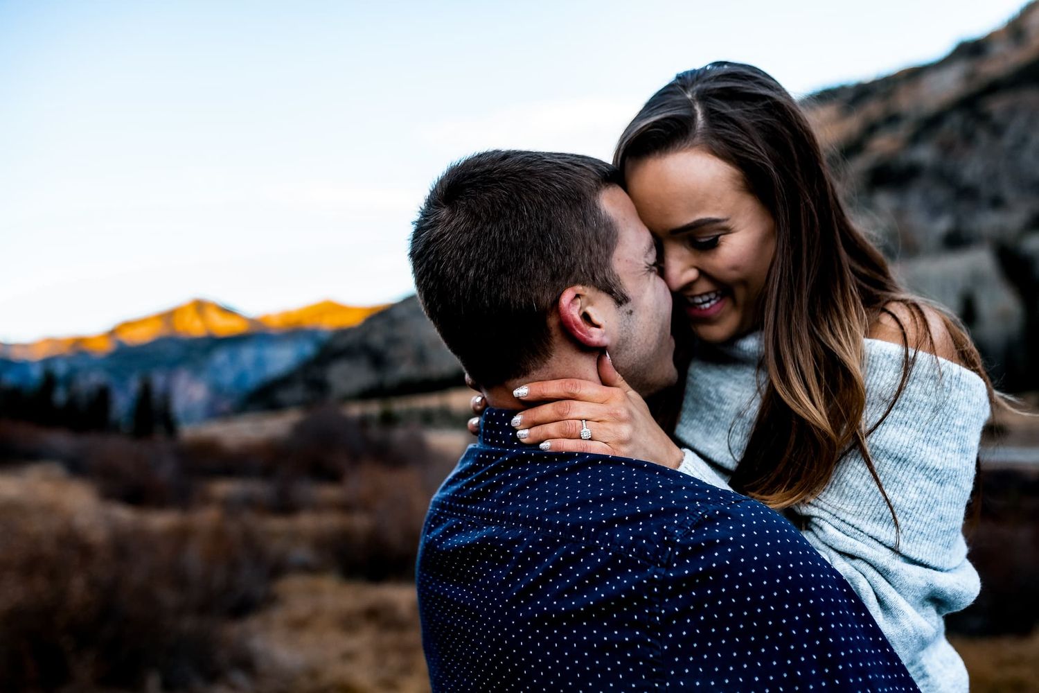 An intimate moment between a couple against a mountain backdrop.