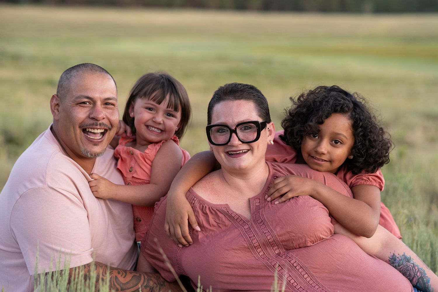 A family cuddles close together in a grassy field during a photo session.