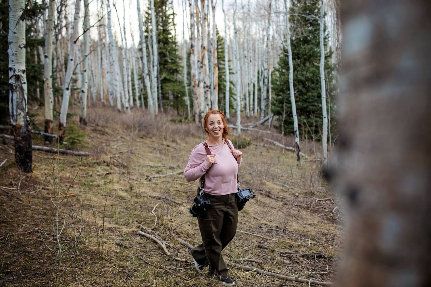 A photographer in Montrose Colorado explores a mountain path surrounded by bare aspen trees.