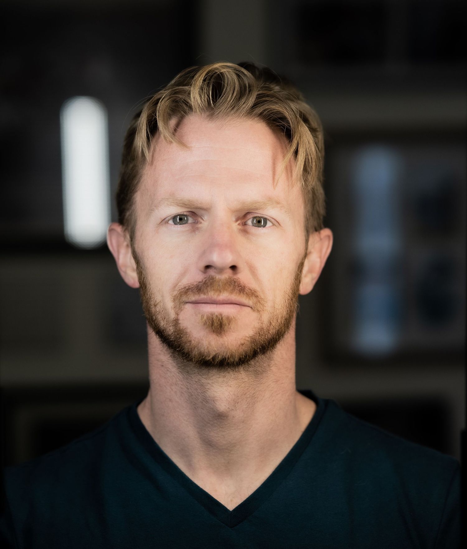 A close-up portrait shot against a dark indoor background.