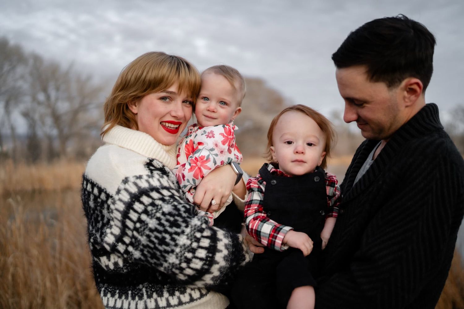 A happy family shares laughter while posing together in winter attire.