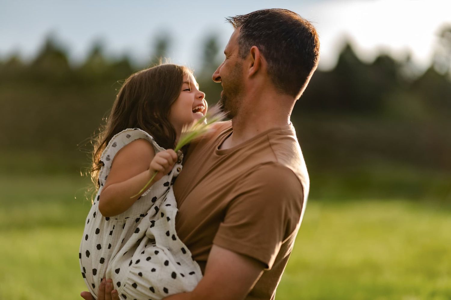 A joyful embrace between parent and child in a sun-drenched field.