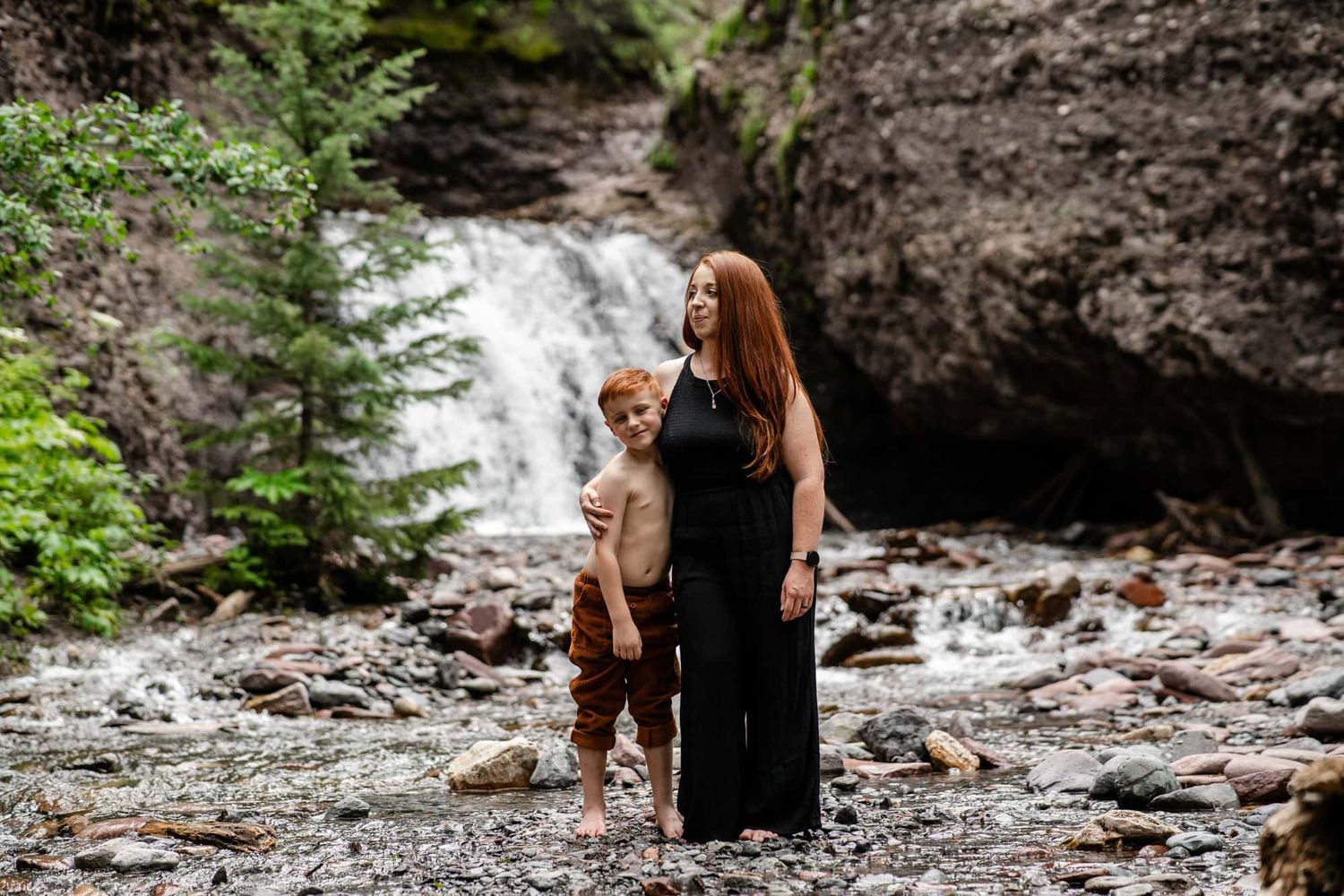 People exploring a scenic waterfall surrounded by rocky terrain and lush forest. Captured by a Photographer located in Telluride Colorado.